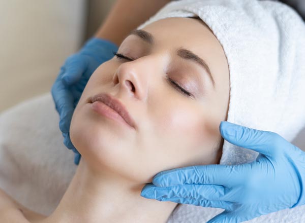 Close-up of a woman receiving a relaxing facial treatment with gloved hands, highlighting the rejuvenating facial services at Revive Aesthetics Med Spa.